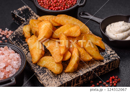 Baked potato wedges with cheese and herbs on a dark background 124312067