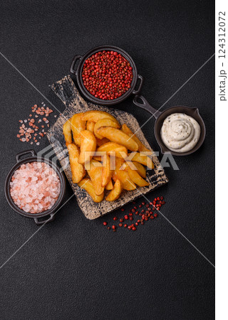 Baked potato wedges with cheese and herbs on a dark background Baked potato wedges with cheese and herbs on a dark background 124312072
