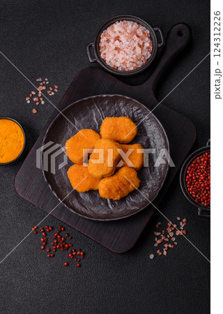 Delicious fresh crispy chicken nuggets on a dark concrete background Delicious fresh crispy chicken nuggets on a dark concrete background 124312226