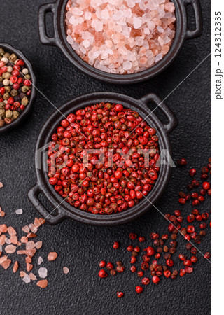 Spice, allspice peas in red or pink color in a bowl on a black concrete background Spice, allspice peas in red or pink color in a bowl on a black concrete background 124312335