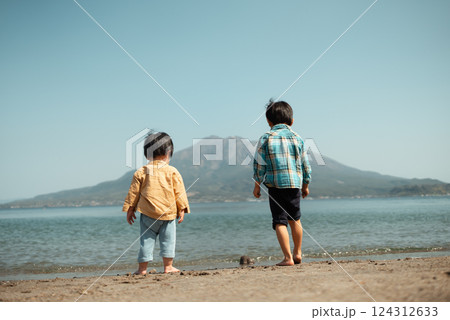 桜島を望む鹿児島の浜辺で遊ぶ兄弟 124312633