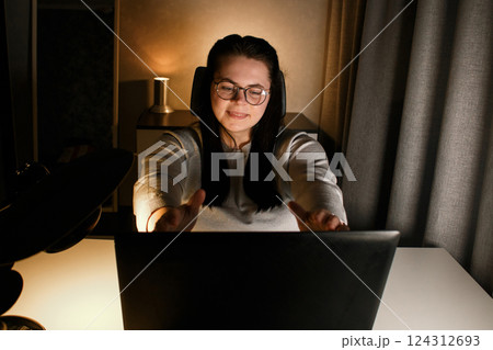 Cheerful millennial woman enjoy videocall with friends using laptop. Gesturing and smiling. Talking with friends who living far. Cherishing long distance friendship. 124312693