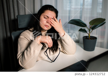 Stressed ang exhausted businesswoman with eye strain removes eyeglasses to reduce eye pain. Overworking concept 124312712