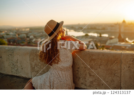 Young female tourist looking at panoramic view of the city at sunset. Lifestyle, travel, active life Young female tourist looking at panoramic view of the city at sunset. Lifestyle, travel, active life 124313137