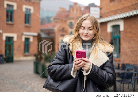 Young stylish 30s woman writes message on smartphone walking on city street. Urban lifestyle concept. Autumn time. Charming female wearing stylish outfit chatting online. High quality photo. Young stylish 30s woman writes message on smartphone walking on city street. Urban lifestyle concept. Autumn time. Charming female wearing stylish outfit chatting online. High quality photo. 124313177