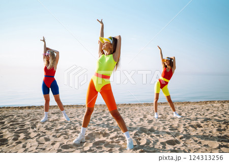 Smiling dancers in colorful swimsuits are dancing on beach ?oncept of sports, aerobics. Active sport 124313256