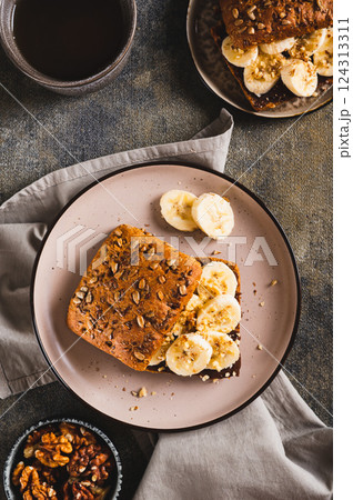 Toast rye bread with chocolate and banana on a plate on the table top and vertical view 124313311
