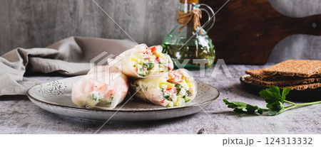 Spring rolls in rice paper with crab sticks, cucumber, greens and sauce on a plate on web banner Spring rolls in rice paper with crab sticks, cucumber, greens and sauce on a plate on web banner 124313332