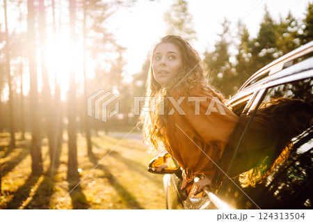 Shot of an attractive woman leaning out of car window while driving. Active lifestyle, travel. 124313504