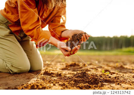 Close-up of experienced woman farmer's hands holding fresh soil. Concept of growing lard, ecology. 124313742
