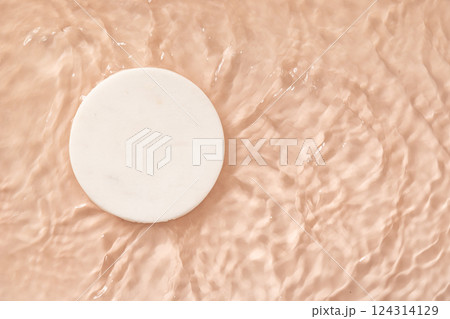 Decorative marble white podium for cosmetics in water on pink nude beige background for product placement. Copy space. Top view 124314129