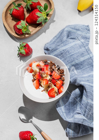 Natural Greek yogurt with homemade chocolate granola, strawberries and banana in a bowl 124314150