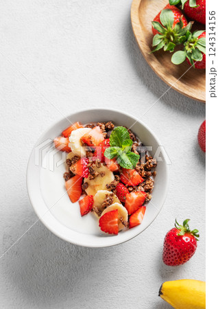 Natural Greek yogurt with homemade chocolate granola, strawberries and banana in a bowl 124314156