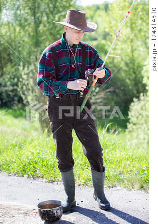 An adult man with a fishing rod and in rubber boots is going fishing. An adult man with a fishing rod and in rubber boots is going fishing. 124314310