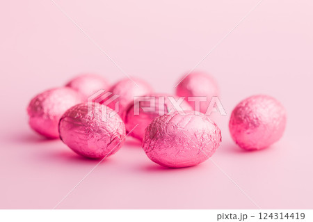Chocolate easter eggs wrapped in pink colored foil on pink background. 124314419