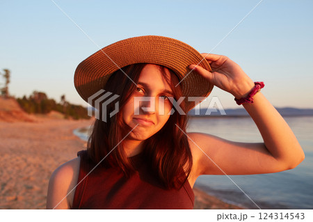 An attractive girl in a straw hat on a sandy beach at sunset. Summer travel, sea holidays An attractive girl in a straw hat on a sandy beach at sunset. Summer travel, sea holidays 124314543