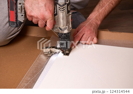 Installing a furniture hinge on a door, assembling furniture and fastening fittings.  Installing a furniture hinge on a door, assembling furniture and fastening fittings.  124314544