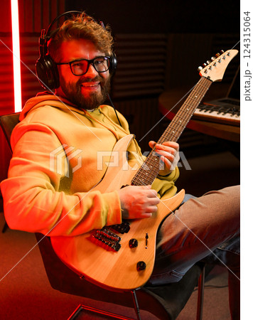 Man vocal artist singing in a recording studio with guitar. Male singer singing a song and playing guitar. Sound record and music streaming concept 124315064