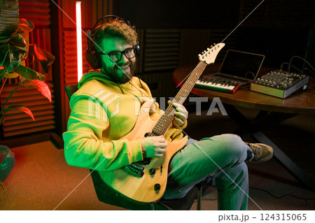 Man vocal artist singing in a recording studio with guitar. Male singer singing a song and playing guitar. Sound record and music streaming concept 124315065