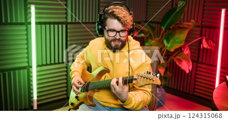 Bearded man playing electric guitar at music studio. Performance and show in the music business, streaming and recording music. 124315068
