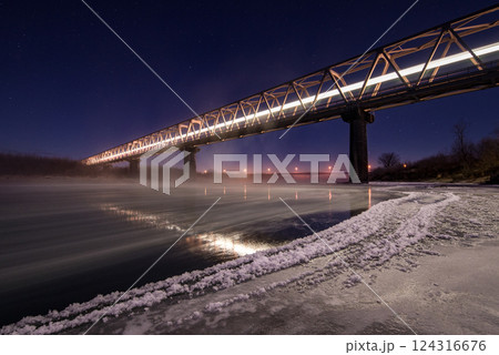北海道の冬の川にかかる鉄橋を渡る列車 124316676