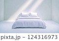 White bed in minimalist room with sunlight streaming in 124316973