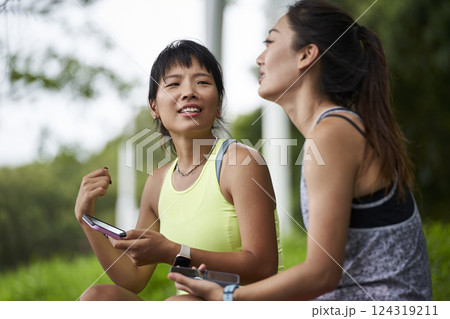 two young asian women female friends relaxing chatting outdoors two young asian women female friends relaxing chatting outdoors 124319211