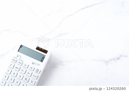 白いテーブルの上の、白い電卓 124320260