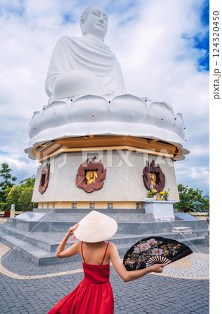 beautiful woman tourist in a Vietnamese hat Buddha statue at Long Son Pagoda in Nha Trang in Vietnam. Tourism and travel in Asia 124320450