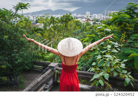 back of happy girl tourist traveler in Vietnamese non la hat in red dress in garden in Vietnam. Tourism and travel in Asia 124320452