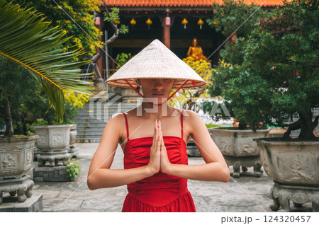woman tourist traveler in Vietnamese hat prays at Long Son Buddhist Pagoda in Nha Trang in Vietnam. Travel and tourism in Asia 124320457