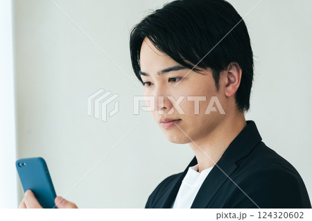 スマホを見て考える若い男性 124320602