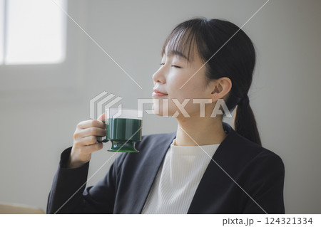 仕事中にコーヒーを飲む女性 仕事中にコーヒーを飲む女性 124321334
