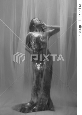 Dreamy Portrait of a Woman in a Silver Dress Behind Sheer Fabric 124322148