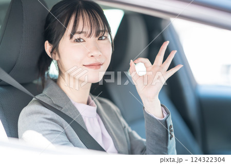 OKポーズをする車に乗ったスーツ姿の若い女性 OKポーズをする車に乗ったスーツ姿の若い女性 124322304
