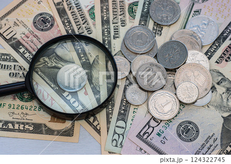 Magnifying glass, different metal coins on paper dollar bills, top view. Magnifying glass, different metal coins on paper dollar bills, top view. 124322745