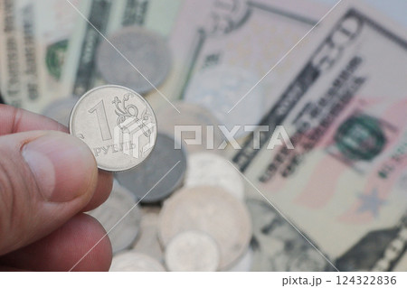 Two fingers of the hand hold a coin of one Russian ruble. 124322836