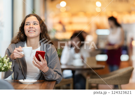 Young woman with phone in cafe Young woman with phone in cafe 124323621