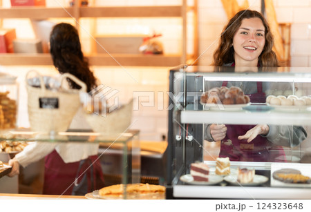 Girl saleswoman works in cafeteria bakery shop Girl saleswoman works in cafeteria bakery shop 124323648