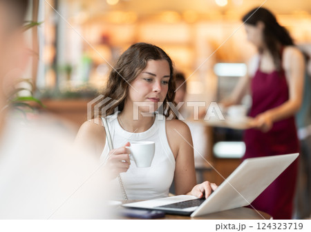 Young woman working at a notebook in a coffee shop Young woman working at a notebook in a coffee shop 124323719