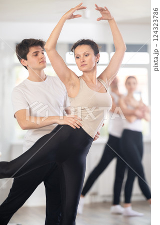 Happy contemporary ballet dancers couple dressed in black and white performing graceful choreography in hall with ballet bar Happy contemporary ballet dancers couple dressed in black and white performing graceful choreography in hall with ballet bar 124323786