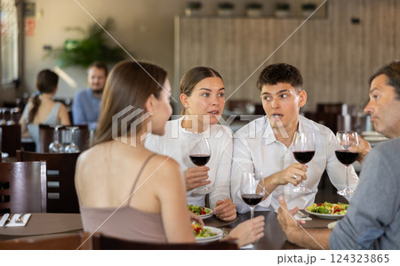 Couples of men and women talking and eating in restaurant 124323865