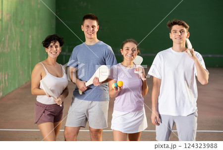 Cheerful pelota players with wooden paletas and rubber balls in outdoor fronton Cheerful pelota players with wooden paletas and rubber balls in outdoor fronton 124323988