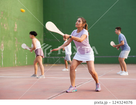 Young Argentinian woman playing pelota at open-air fronton in summer 124324076
