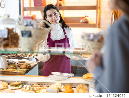 Girl saleswoman works in cafeteria bakery shop Girl saleswoman works in cafeteria bakery shop 124324083