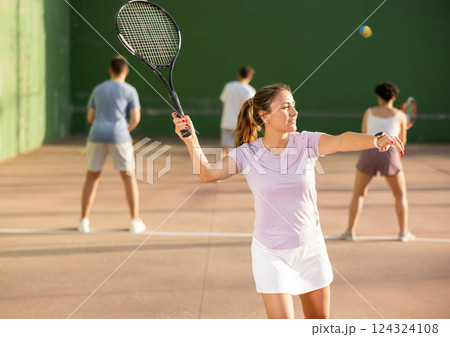 Young hispanic female frontenis player swinging racquet to hit ball Young hispanic female frontenis player swinging racquet to hit ball 124324108