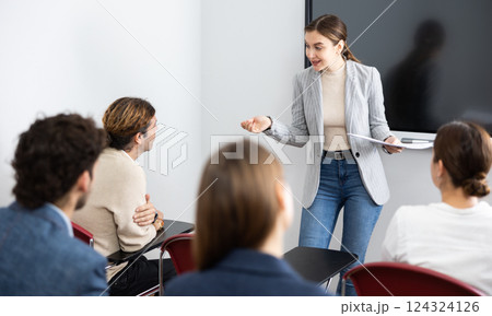 Young female tutor teaching students in college classroom 124324126