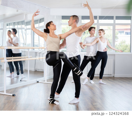 Happy contemporary ballet dancers couple dressed in black and white performing graceful choreography in hall with ballet bar Happy contemporary ballet dancers couple dressed in black and white performing graceful choreography in hall with ballet bar 124324168