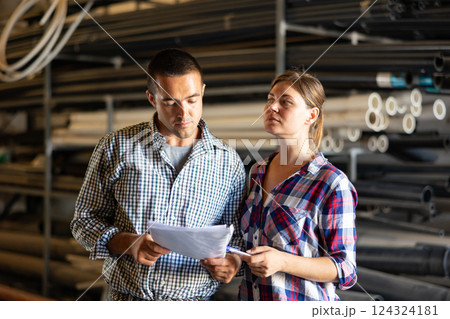 Manager and employee together checking availability of goods in building materials warehouse 124324181
