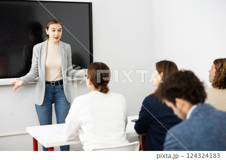 Young female professor explaining subject to classroom full of students 124324183